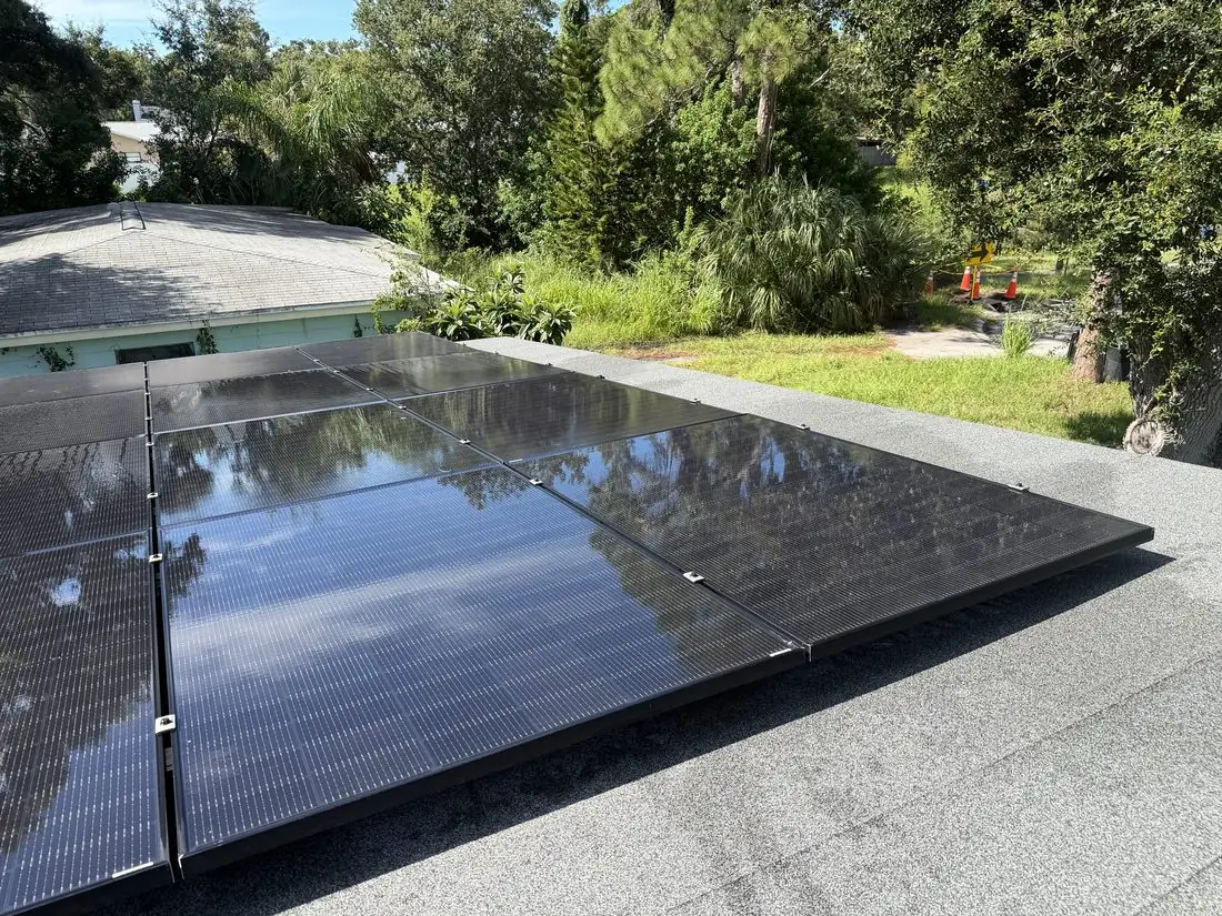 Clean solar panels reflecting a roof treeline